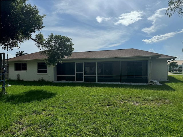 back of property with a sunroom, a yard, and stucco siding