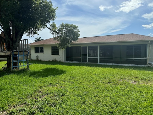 back of property featuring a yard, a sunroom, and stucco siding