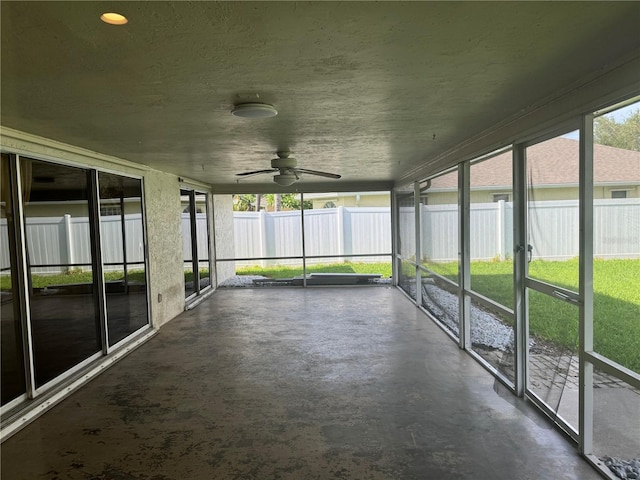 unfurnished sunroom featuring ceiling fan and a healthy amount of sunlight