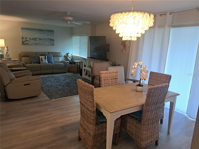 dining room featuring ceiling fan with notable chandelier and wood-type flooring