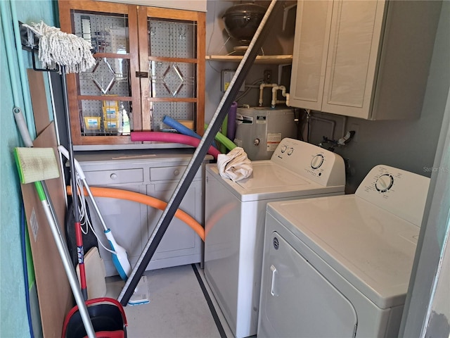 laundry room with washing machine and clothes dryer, electric water heater, and cabinets