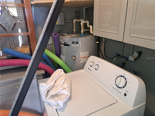 clothes washing area featuring water heater, washer / clothes dryer, and cabinets