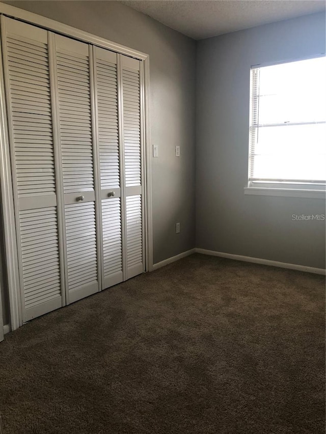 unfurnished bedroom featuring a closet and dark carpet