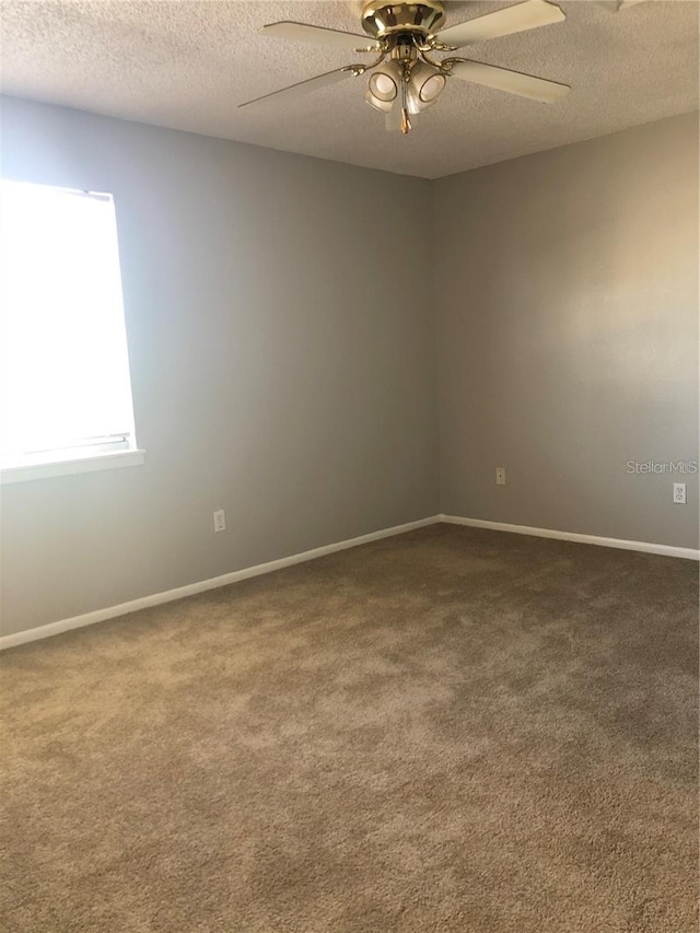 empty room featuring ceiling fan, a textured ceiling, and carpet floors