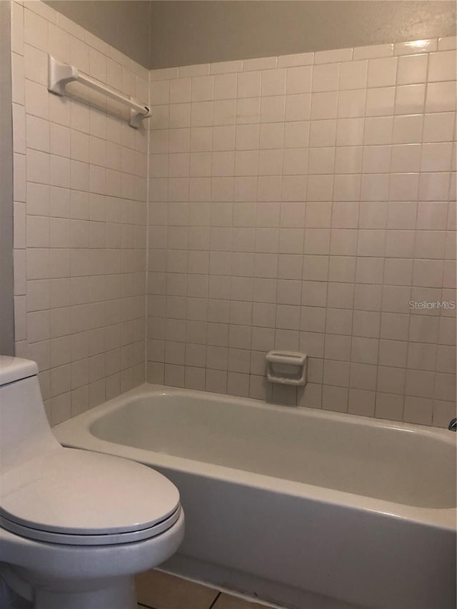 bathroom featuring toilet, tiled shower / bath, and tile patterned floors