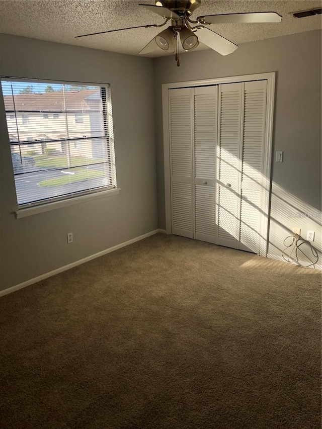 unfurnished bedroom featuring ceiling fan, a closet, a textured ceiling, and carpet