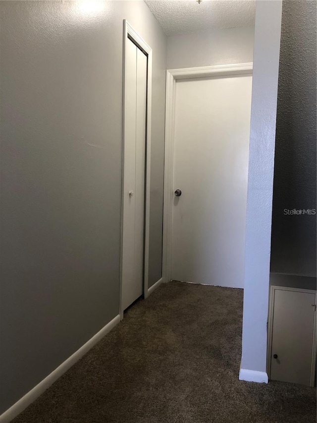 corridor with a textured ceiling and carpet flooring