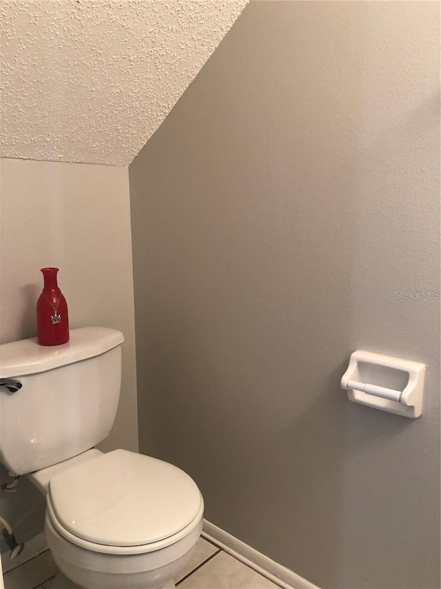 bathroom featuring a textured ceiling, tile patterned floors, toilet, and lofted ceiling