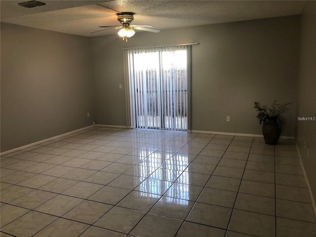 tiled spare room with ceiling fan and a textured ceiling