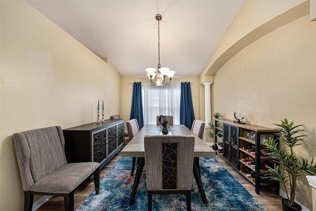 dining room with vaulted ceiling, dark wood-type flooring, and an inviting chandelier