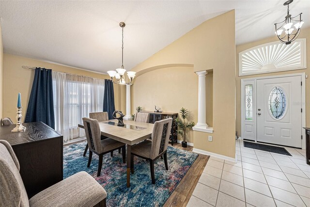 tiled dining area with an inviting chandelier, ornate columns, and lofted ceiling