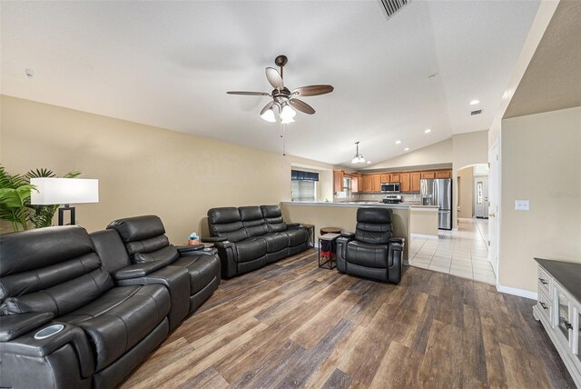 living room with hardwood / wood-style floors, ceiling fan, and vaulted ceiling