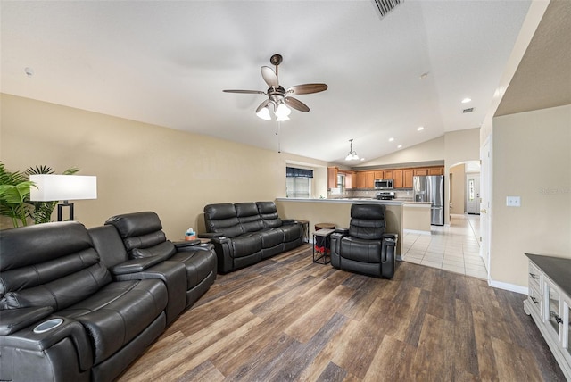 living room with arched walkways, wood finished floors, visible vents, a ceiling fan, and vaulted ceiling