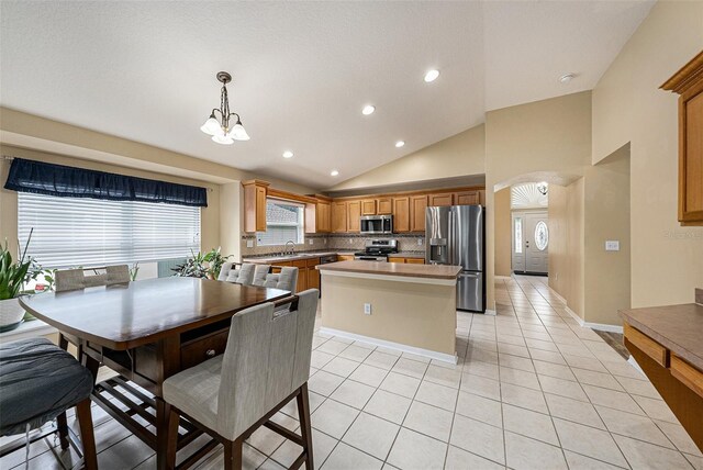 kitchen with stainless steel appliances, light tile patterned floors, a notable chandelier, a center island, and hanging light fixtures