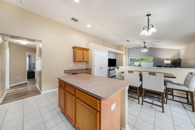 kitchen featuring ceiling fan with notable chandelier, light tile patterned floors, a center island, hanging light fixtures, and lofted ceiling