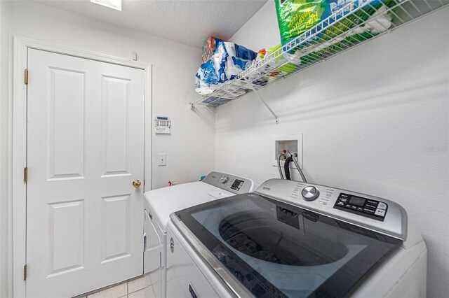 laundry room with light tile patterned flooring, a textured ceiling, and washing machine and clothes dryer