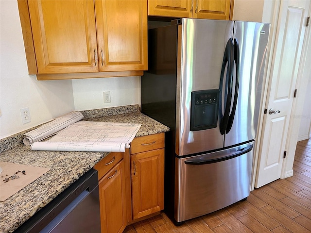 kitchen featuring light wood finished floors, brown cabinetry, and appliances with stainless steel finishes