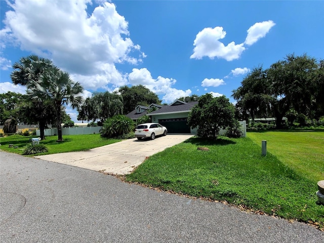 view of front of home featuring an attached garage, concrete driveway, and a front yard