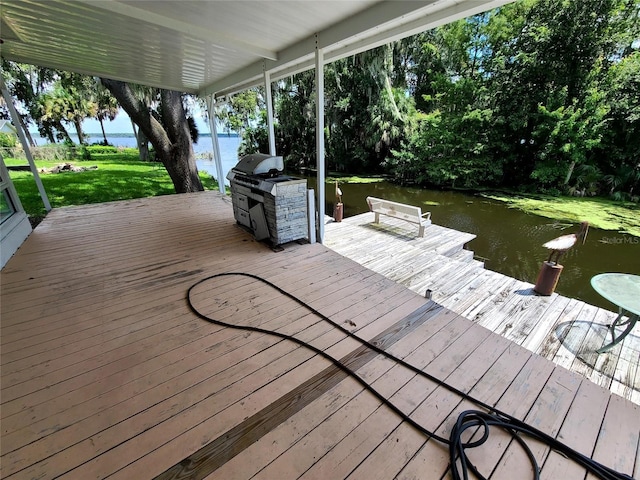 deck featuring grilling area, a water view, and a dock