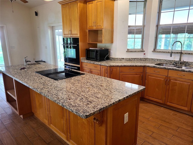 kitchen with wood finished floors, a kitchen island, open shelves, a sink, and black appliances