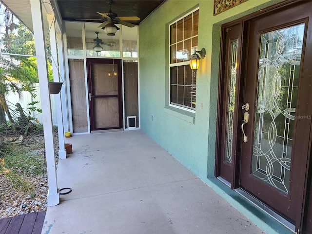 doorway to property featuring stucco siding, a porch, and ceiling fan