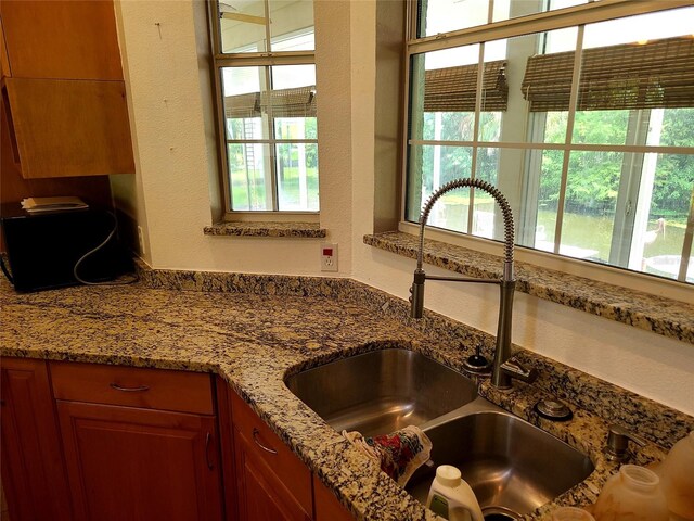 kitchen featuring light stone counters and sink