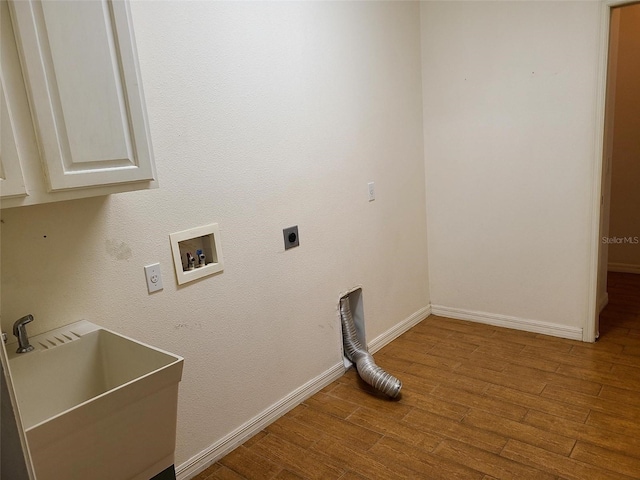 laundry room with wood finished floors, baseboards, hookup for an electric dryer, cabinet space, and a sink