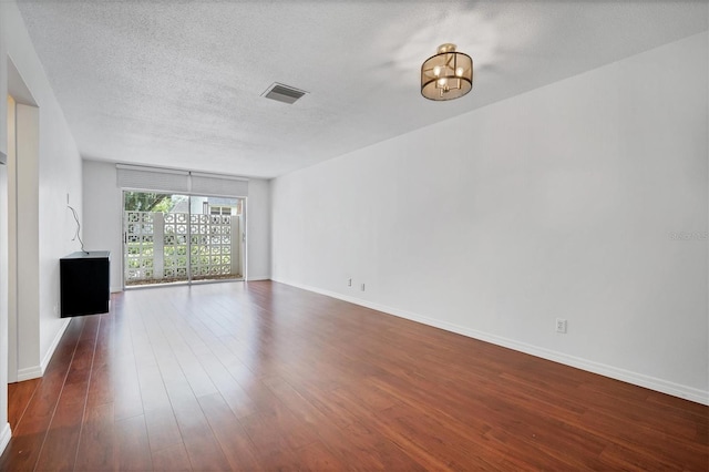 unfurnished living room with a textured ceiling, dark hardwood / wood-style flooring, and a notable chandelier