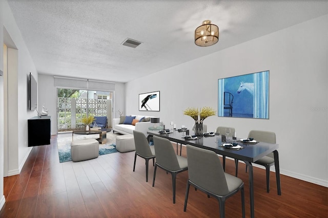 dining space with a textured ceiling, wood-type flooring, and a chandelier