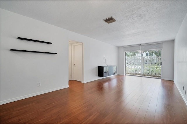 unfurnished living room featuring a textured ceiling, hardwood / wood-style flooring, a chandelier, and a wall of windows