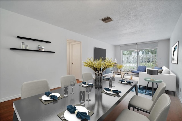 dining area with dark wood-type flooring and a textured ceiling