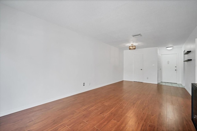 unfurnished room with a textured ceiling and hardwood / wood-style floors