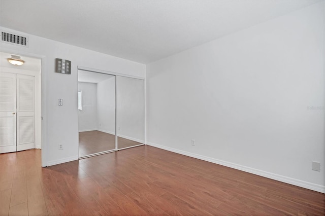 unfurnished bedroom featuring a closet and hardwood / wood-style flooring