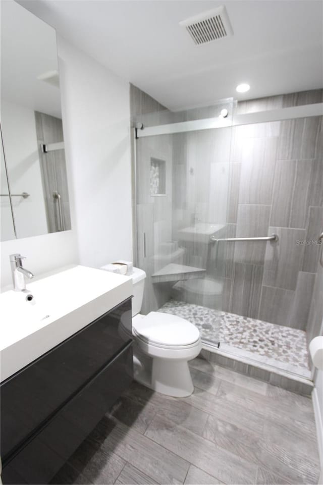 bathroom with a shower with door, vanity, toilet, and hardwood / wood-style flooring