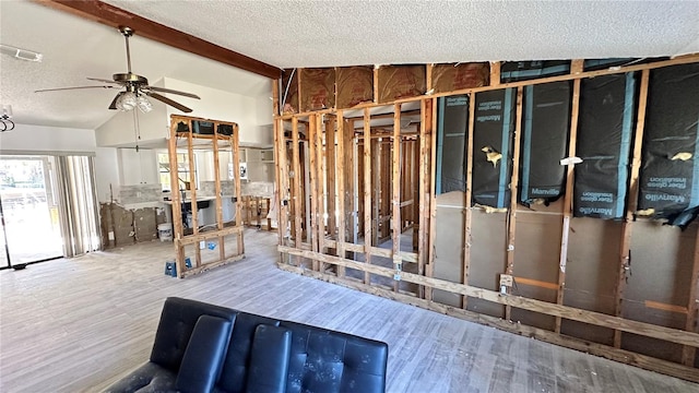 misc room featuring ceiling fan, wood-type flooring, a textured ceiling, and vaulted ceiling with beams