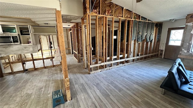 miscellaneous room with lofted ceiling, hardwood / wood-style floors, and a textured ceiling