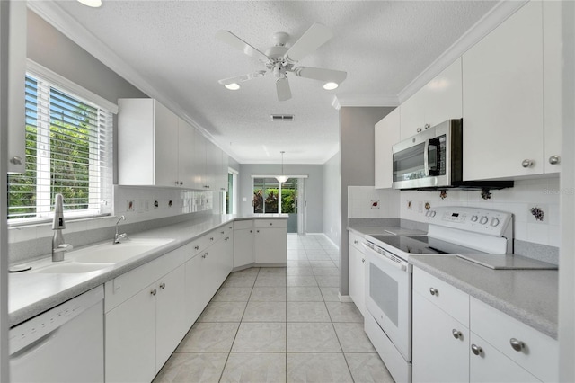 kitchen with a textured ceiling, white appliances, white cabinetry, and pendant lighting