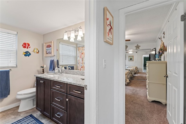 bathroom with toilet, ceiling fan, vanity, and plenty of natural light