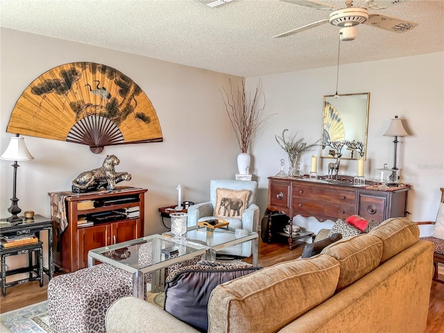 living room with ceiling fan, wood-type flooring, and a textured ceiling