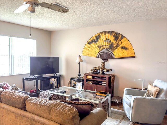 living room featuring a textured ceiling, ceiling fan, and light wood-type flooring