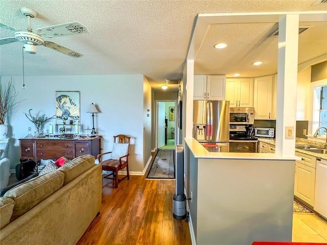 kitchen featuring stainless steel appliances, sink, wood-type flooring, a textured ceiling, and white cabinets