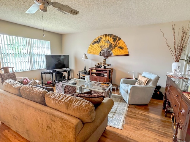 living room with a textured ceiling, ceiling fan, and hardwood / wood-style floors