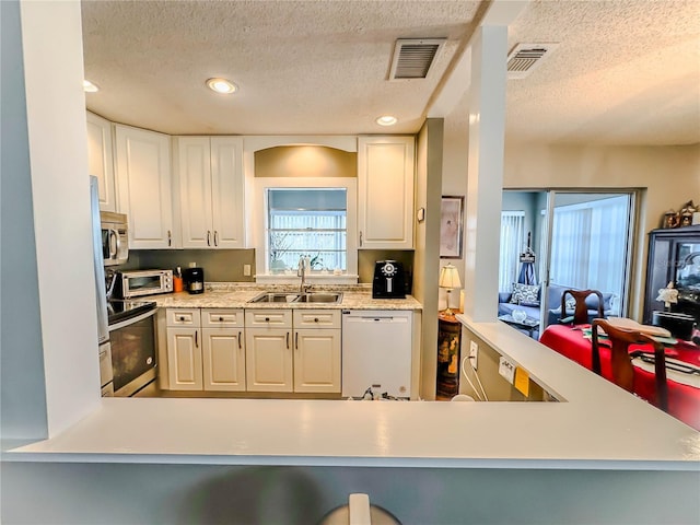 kitchen with sink, stainless steel appliances, white cabinetry, and a textured ceiling