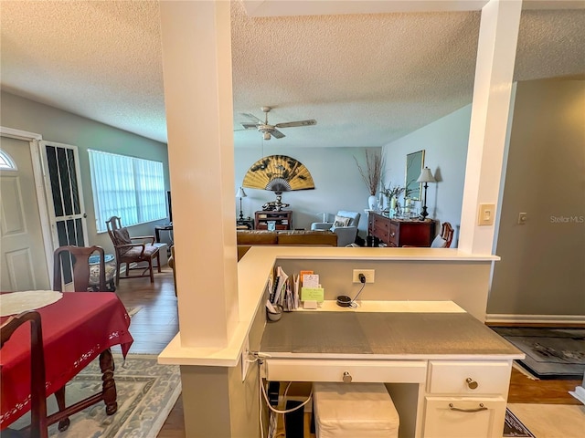 kitchen with light hardwood / wood-style floors, ceiling fan, kitchen peninsula, white cabinets, and a breakfast bar area