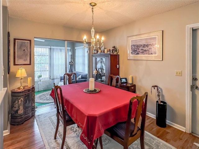 dining space featuring hardwood / wood-style flooring, a textured ceiling, and an inviting chandelier