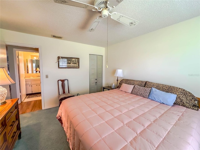 bedroom with ceiling fan, a closet, ensuite bath, hardwood / wood-style flooring, and a textured ceiling