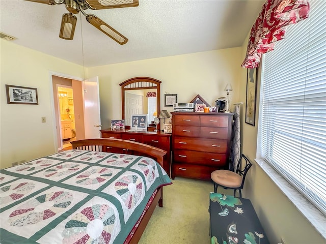 bedroom featuring a textured ceiling, ceiling fan, connected bathroom, and light colored carpet