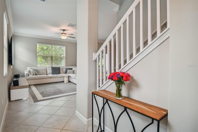 living room featuring ornamental molding, light tile patterned flooring, a ceiling fan, and baseboards