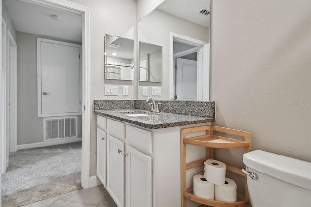 bathroom featuring toilet, vanity, visible vents, and baseboards