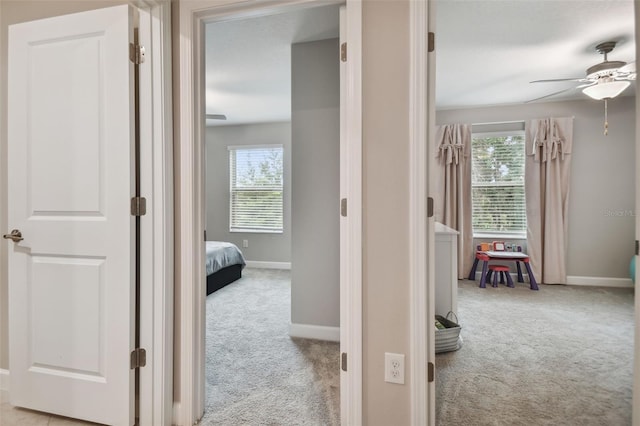 hallway with light carpet, baseboards, and a wealth of natural light